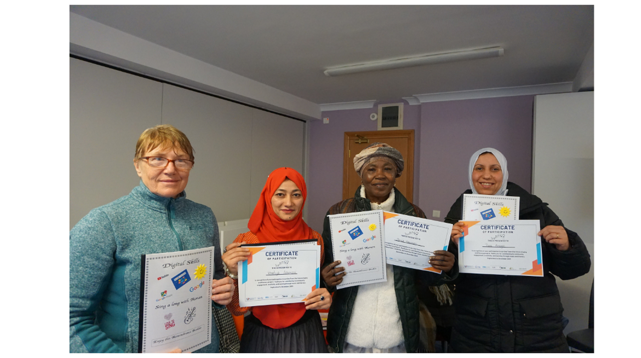 Four people stand indoors, smiling and holding certificates of participation in a digital skills course.